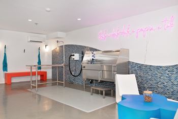 A kitchen with a grill and a table and a pink neon sign